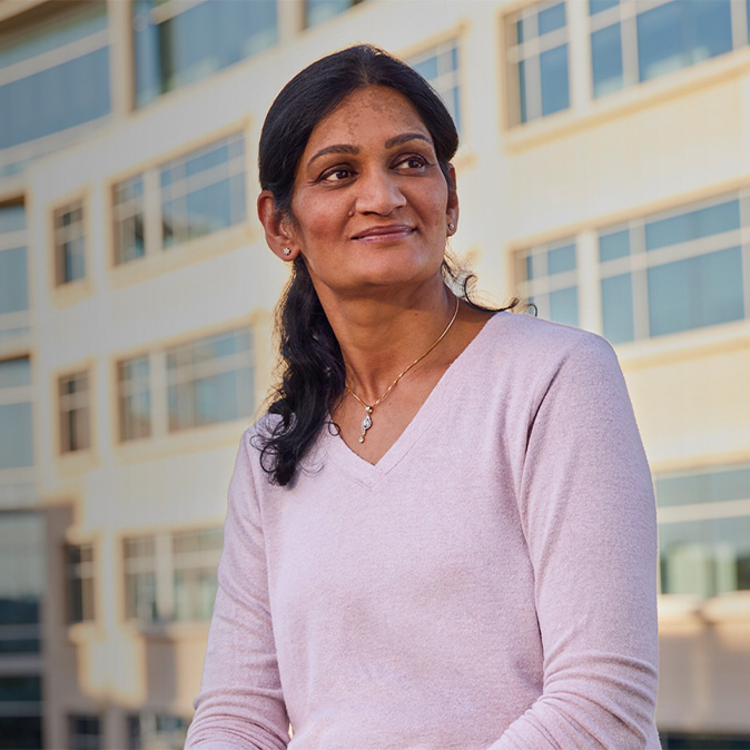Ramani, der sidder uden for en kontorbygning, kigger til siden.