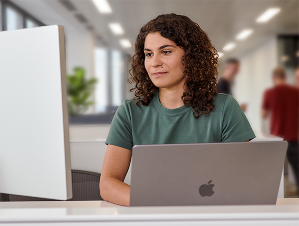一位 Apple 團隊成員在辦公室使用 MacBook 和 Studio Display。