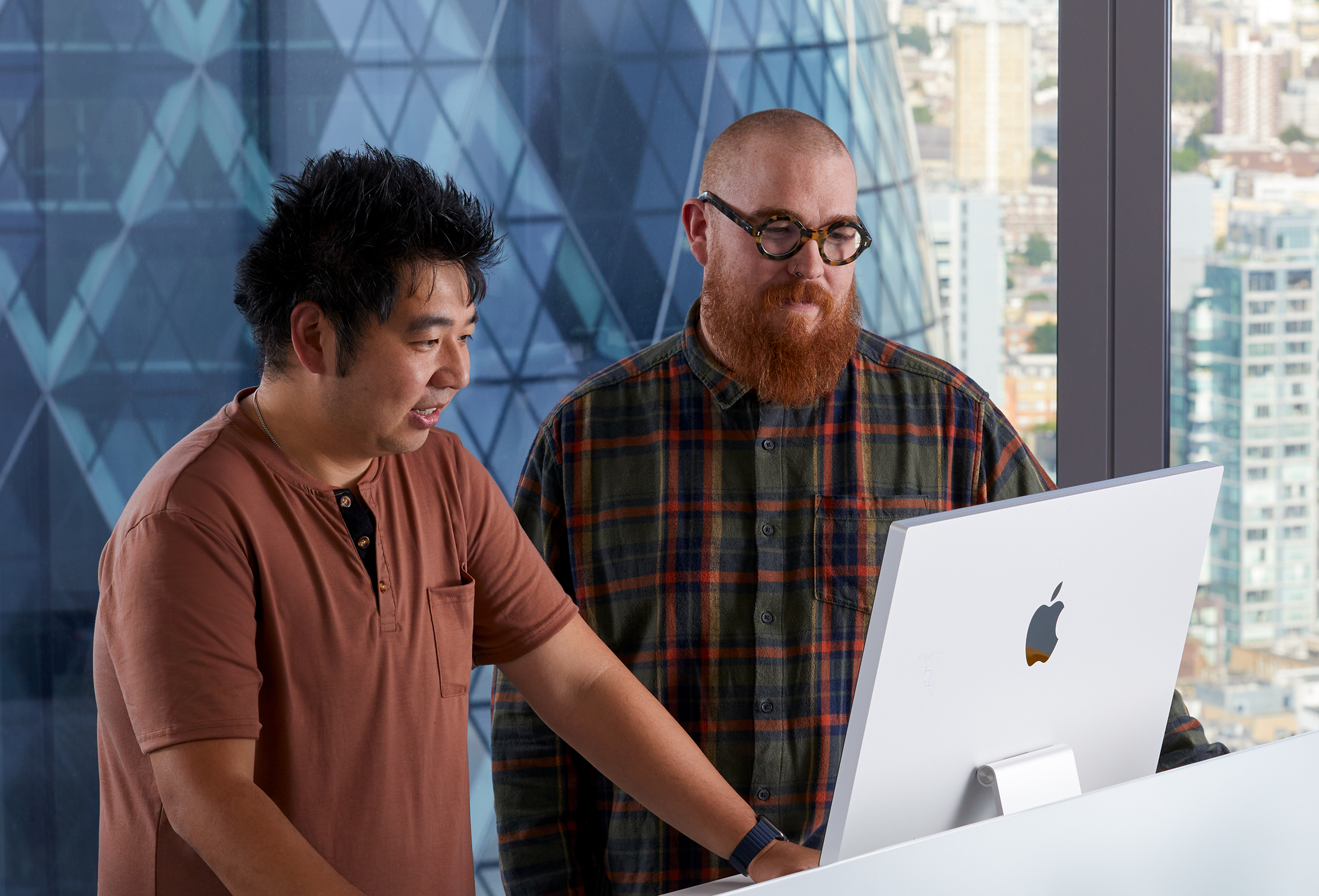 兩位 Apple 同事正在使用 iMac 合作。