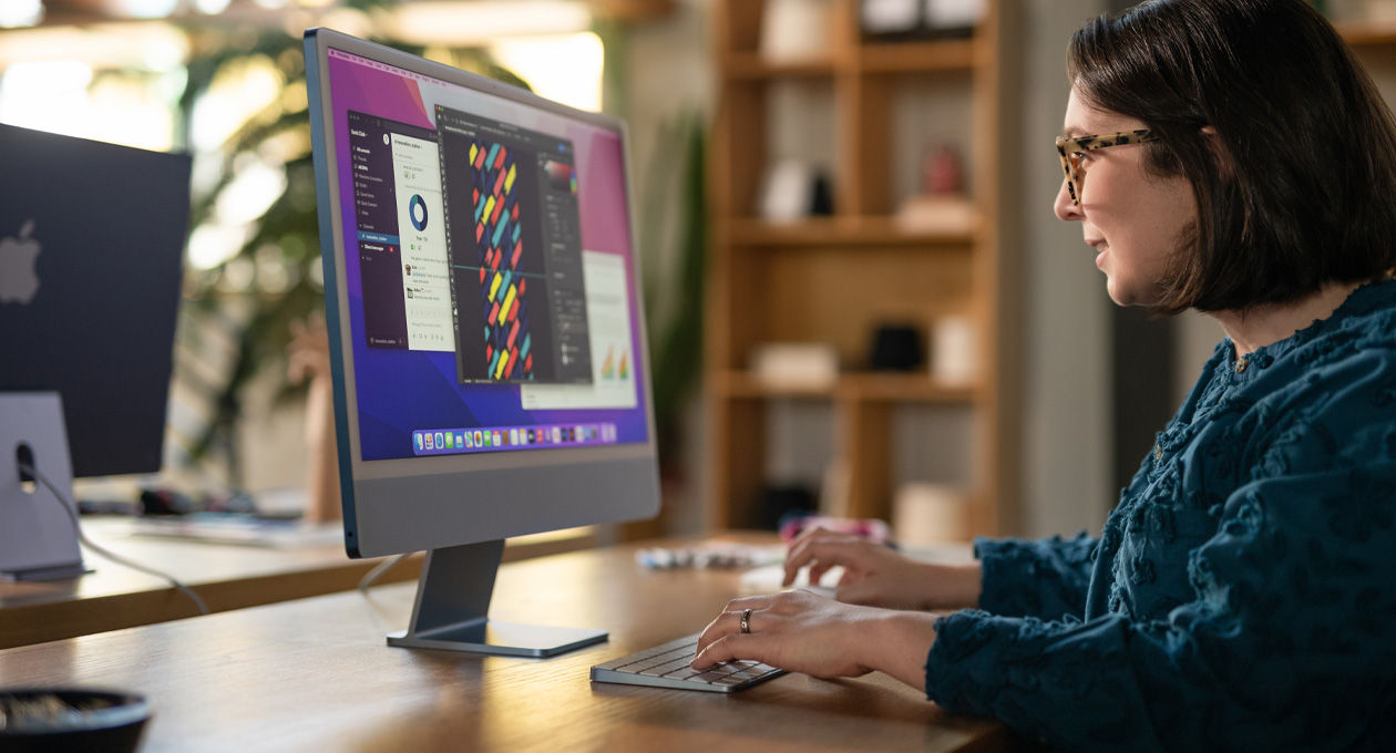 Uma pessoa trabalha em um iMac que exibe um app de design colorido em um ambiente profissional