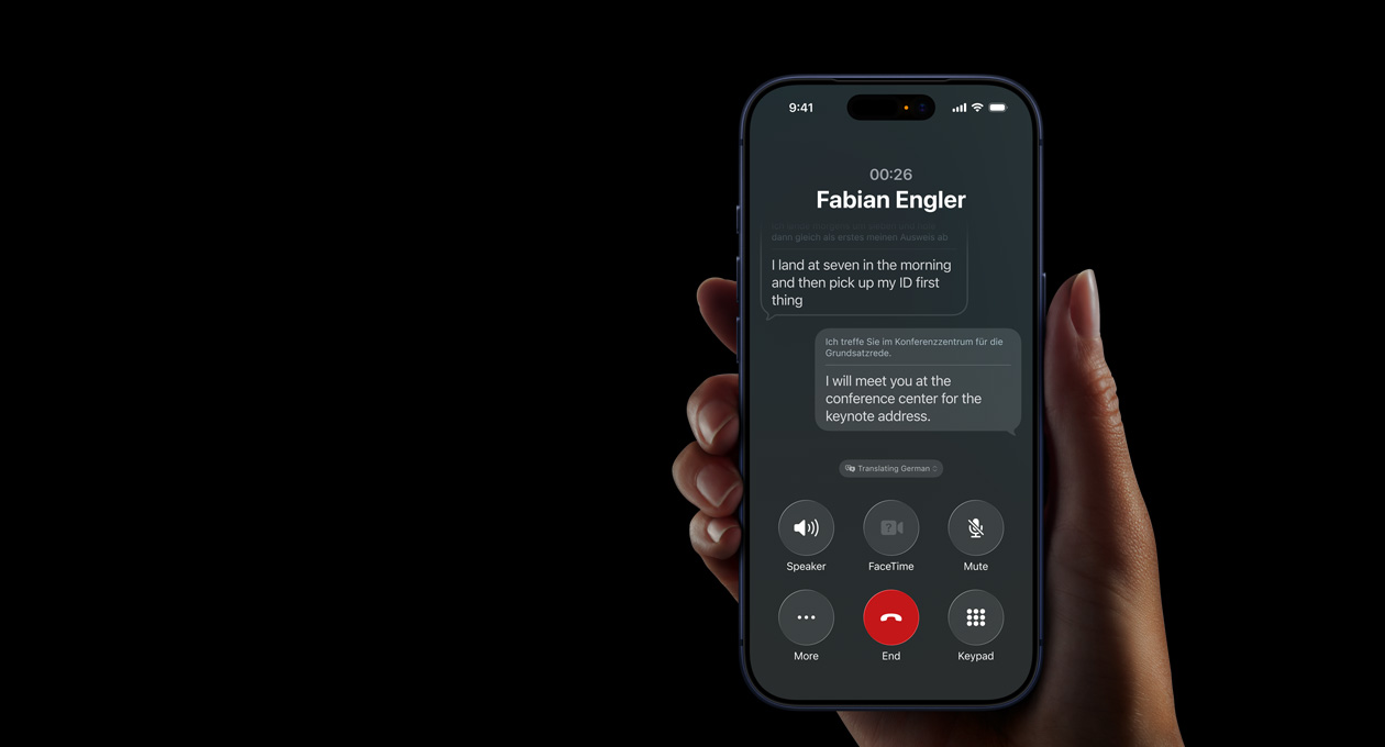 Ruka drží iPhone 17 Pro s ukázkou okamžitého tlumočení pomocí Apple Intelligence při telefonátu se zapnutým hlasitým reproduktorem.